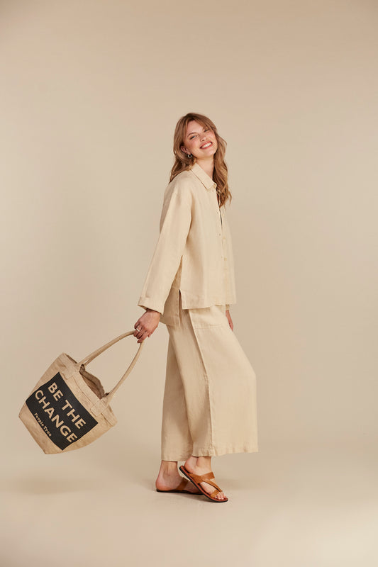 Woman wears stone coloured organic linen shacket & trousers from People Tree