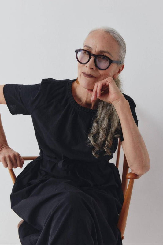 Woman wearing an elegant black cotton dress sitting on a chair