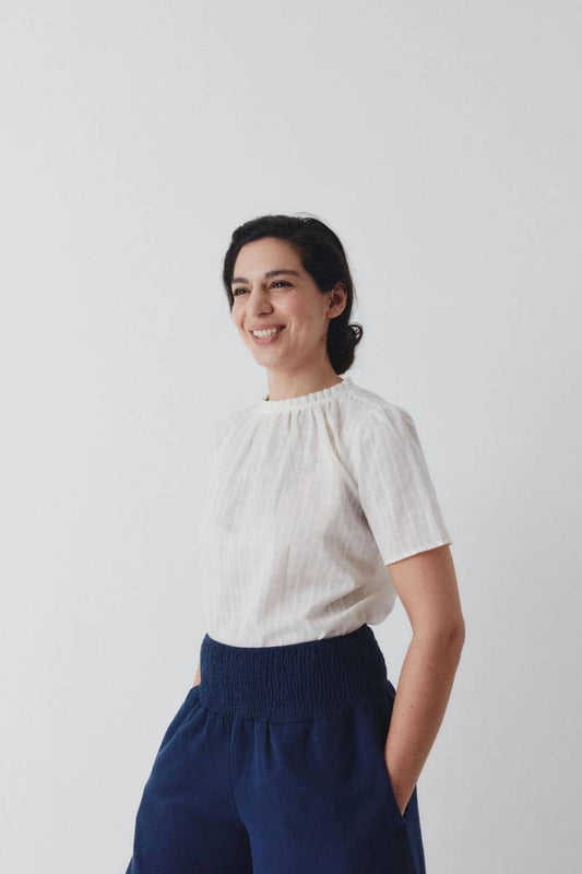 Woman wearing an elegant white blouse with short sleeves.